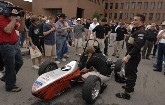 crowd gathered around a small Formula car.