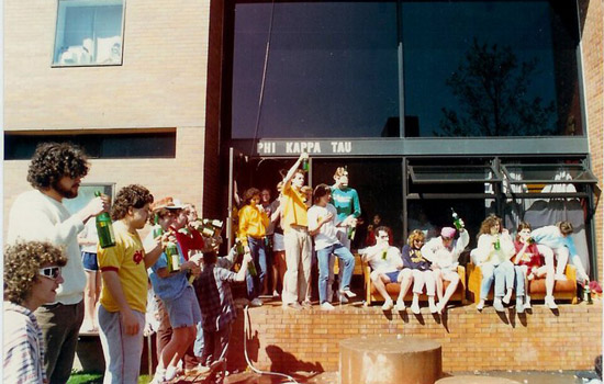 college students drinking bottles of champagne outside in the 1980s.