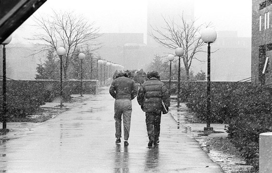 pair of college students walking to class in the snow in 1975.