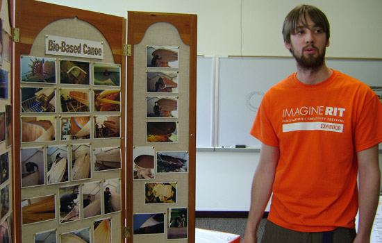 college student standing in front of a display of canoe photos..