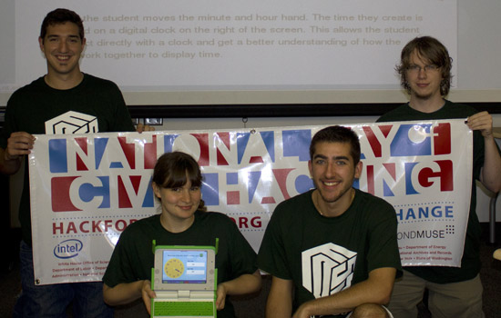 Four people posing with computer at event