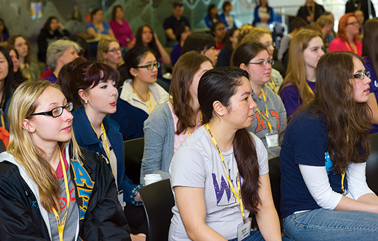  students sitting in chairs while getting a demo.