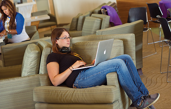 student sitting in chair looking at laptop.