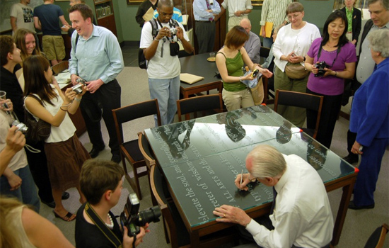 People walking around table with enscriptions