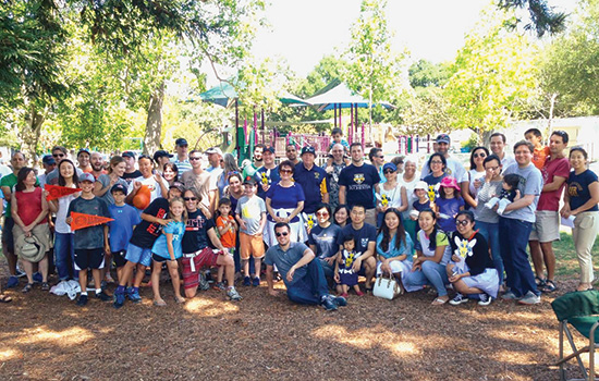 large group of people posing in front of a playground.