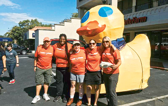 five people posing in front of a duck parade float.