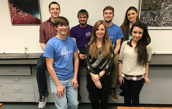 seven people pose for team two in a classroom.