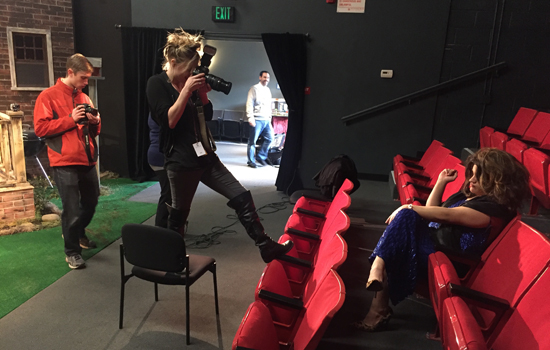 photographer taking photo of actor sitting in a theater chair.