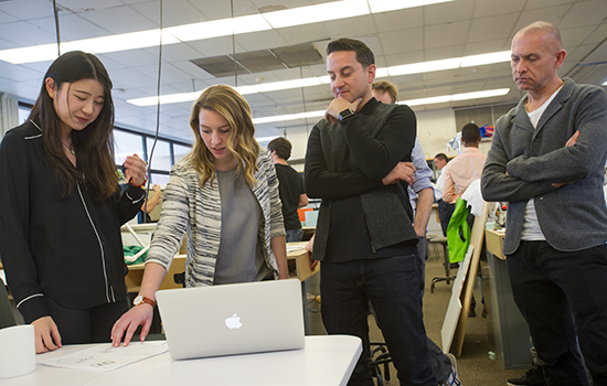 4 people looking at something on a laptop