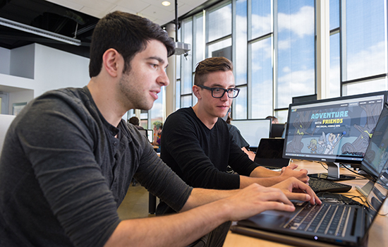 two students looking at laptop screen.