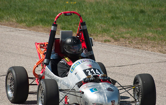 Person driving formula car down pathway