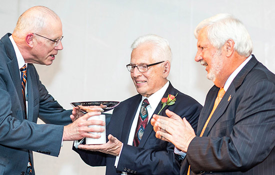 Three People in award acceptance ceremony
