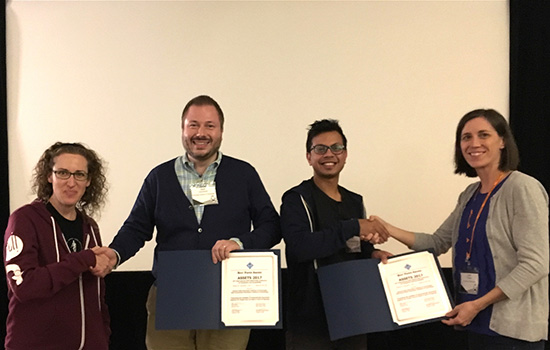  four people shaking hands while holding certificates smiling.