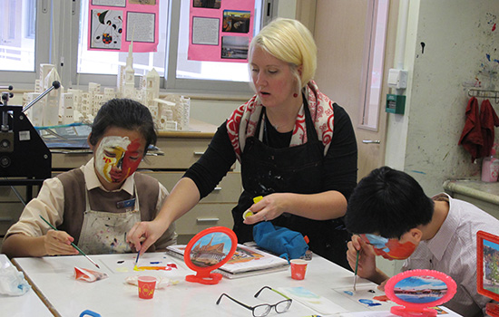  person teaching two kids to paint at a table.