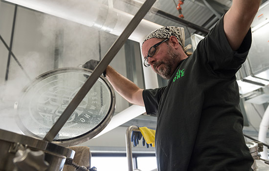 person stirring vat of beer.