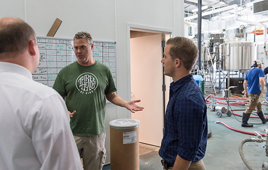 three people talking in brewery.