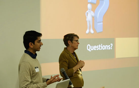 2 presenters in front of a projection screen.