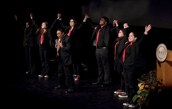 group of college students holding hands with their arms raised in the air.