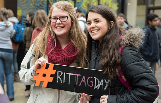 two people holding sign that says hashtag rit tag day.