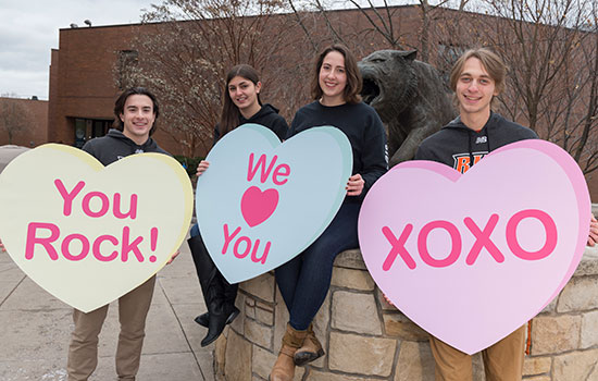  three students holding big conversation hearts.