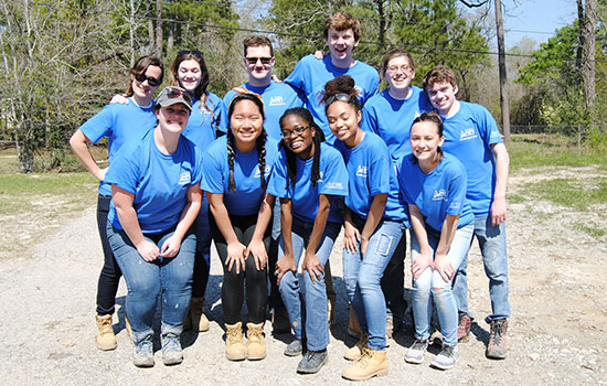 group poses for a photo wearing matching blue shirts.