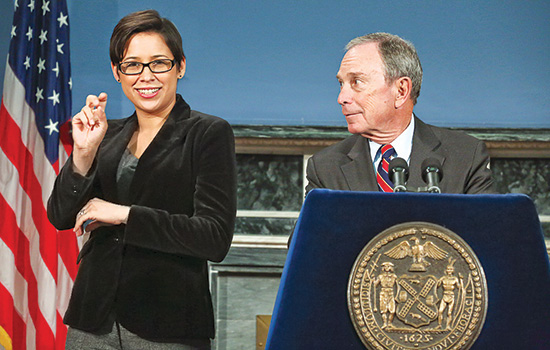 Lydia Callis signing next to New York City Mayor.