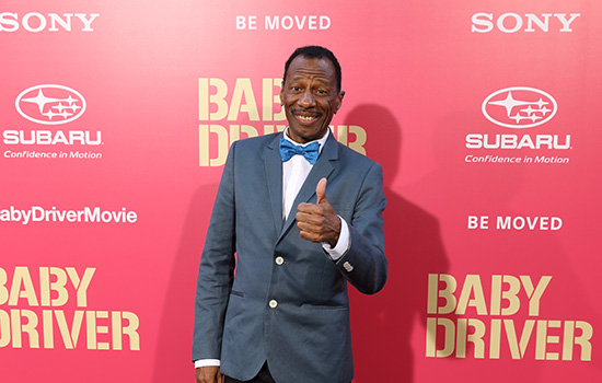 CJ Jones giving a thumbs up in front of a pink background.