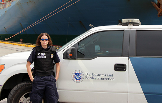 Jacquelyn Wilson leaning up against U.S. Customs and Border Protection car in uniform.