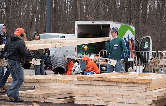  students carrying wooden frames outside for a construction project.