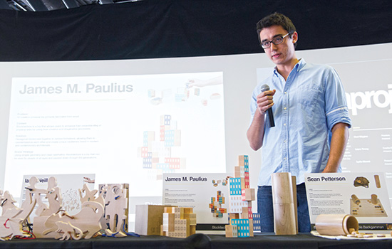 a person lecturing behind a table of wooden art