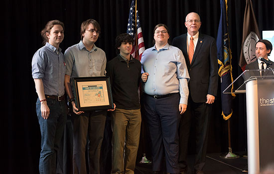  four students holding certificate next to president munson.