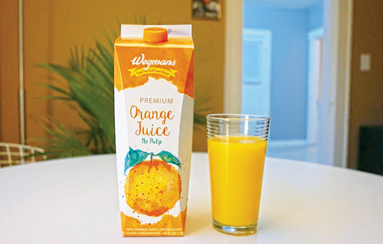 a glass of orange juice next to a sustainably designed orange juice bottle.