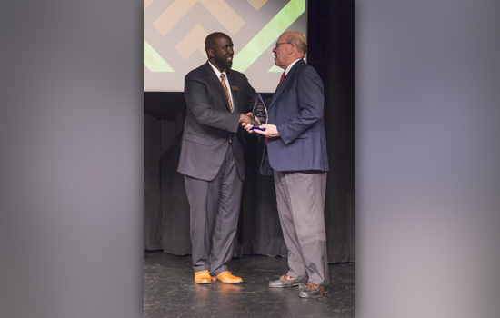  two people shaking hands with award.