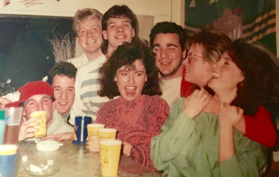 Group of friends pose together for photo at a party with cups in front of them.