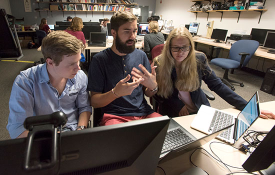 three undergrad students looking at computer screens.