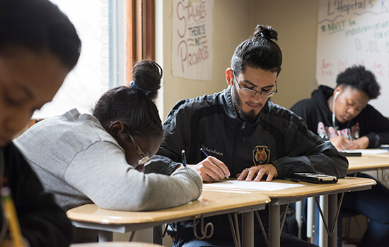 students writing math at desks in a classroom.