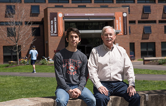 student and grandfather sitting in front of dorm.