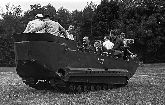  people sitting in a personnel carrier in the 1960s.