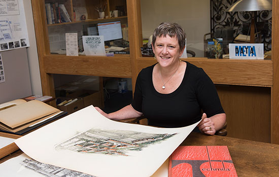 Becky Simmons sitting with architectural sketches.