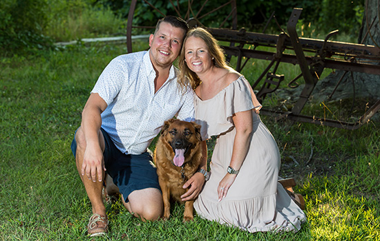 two people posing with their dog.