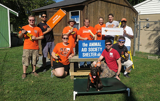 volunteers posing with power tools and a shelter dog.