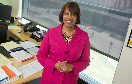 Twyla Cummings standing in office wearing a hot pink blazer.