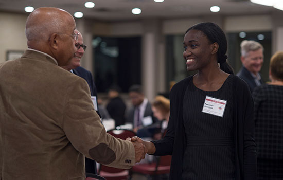 scholar shaking hands with faculty.