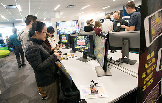 group of students standing in front of computer monitors playing games.