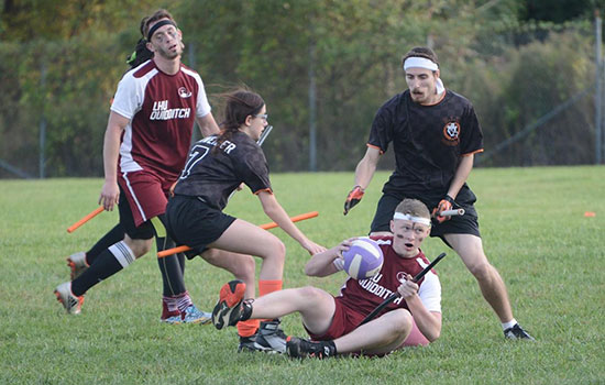 four college students playing quidditch.