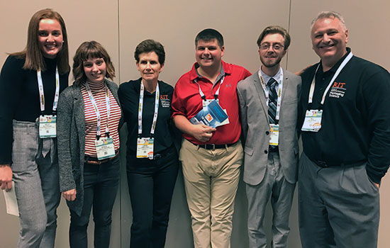 Team winners pose for picture. Each has a lanyard around their neck.