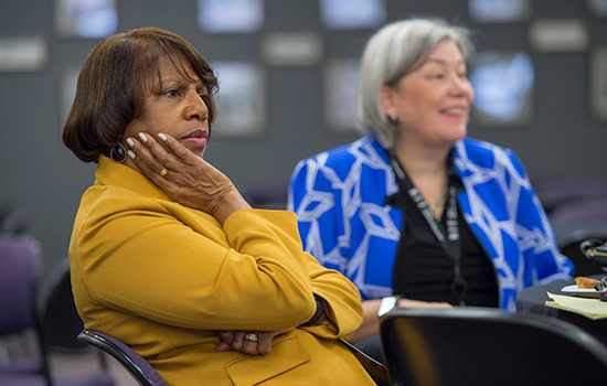 two women observing showcase presentation.