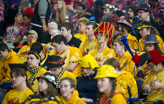 crowd wearing fun hats and matching yellow shirts in a competition event.
